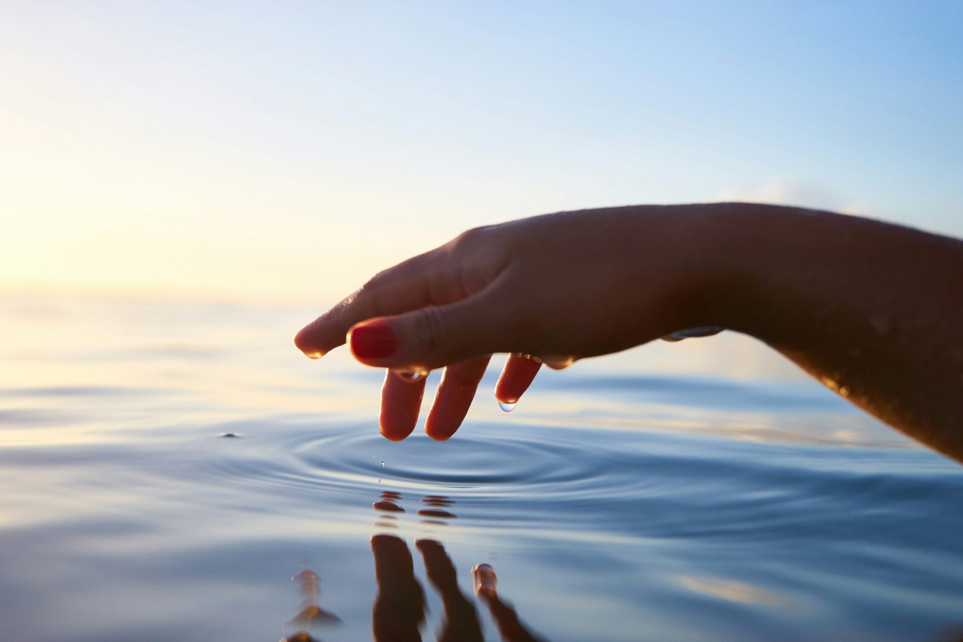 Une main sortant délicatement de l'eau laisse les gouttes retomber délicatement